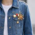 Close-up of a vintage sun and heart charm brooch styled on a blue denim jacket. - Vintage Face Sun Style (26Y0006)