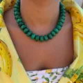 Close-up detail of a bohemian green resin beaded necklace worn with a yellow floral shirt - Dark Green