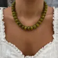 Close-up detail of bohemian olive green resin beaded necklace with marbled texture on model - Olive Green