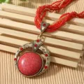 Macro view of Bohemian vintage necklace featuring red stone pendant and woven seed beads - Red