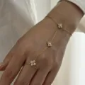Vue détaillée d'une chaîne de main en acier doré avec des breloques fleurs en zircon. - Bracelet avec Bague (BR26Y0295)