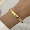 Gedetailleerde macro-opname van een gouden roestvrijstalen armband met sterren en kristallen. - Goud (Ster Gepubliceerd Gegraveerd Vintage Strass)