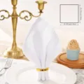 White cotton linen napkin detail view with gold ring on elegant dining table setting. - 48x48cm / White