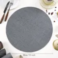 Detail shot of a round gray PU leather placemat with woven texture for modern dining table decor. - Textured Leather / Grey Blue