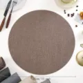 Detail view of the premium brown round PU leather placemat, waterproof and heat-insulating. - Textured Leather / Coffee