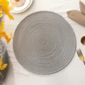 Gedetailleerde close-up van een ronde grijze gevlochten placemat met gouden spiraldraad. - Zilvergrijs met Goudraad