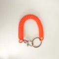 Primo piano del portachiavi a spirale arancione vivace, cordino elastico da polso con robusta fibbia. - Arancione