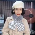 Detailed shot of a stylish plush checkered cross scarf worn with a chic white beret. - Grey Checkerboard