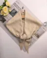 Detail van beige gebreide driehoekige sjaal, zachte wolblend stof, elegant dagelijks accessoire. - Beige