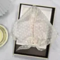 Detailweergave van transparante organza driehoekige sjaal met klassiek wit stippenpatroon. - Lichtgeel