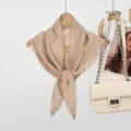 Gedetailleerd overzicht van beige linnen driehoekige sjaal met elegant kanten randje. - Kaki