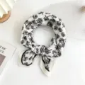Gedetailleerd close-up van een witte katoenen vierkante sjaal met zwarte rozenprint. - Stijl 9