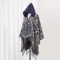 Detailaufnahme eines böhmischen Strickponchos mit Kapuze, Ethno-Muster und Fransen. - Marineblau