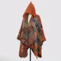 Detailansicht eines gestrickten Ponchos mit Kapuze, Tribal-Mustern und warmen Tönen. - Cape-Stil / Karamellbraun