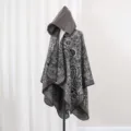 Detailansicht eines grauen Paisley-Strickponchos mit Kapuze auf einer Schaufensterpuppe - 135*150CM / Grau