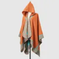 Detailansicht eines orangefarbenen Strickponchos mit Kapuze und blauem Muster - Orange