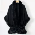 Detail view of elegant black knit cape with plush faux fur collar and trim detail. - Tops / Black
