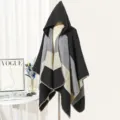 Detailed view of a hooded color-block knitted poncho in black and grey tones. - Black