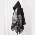Detailansicht eines schwarzen Ponchos mit Kapuze und eleganten weißen Blumenmustern. - Oberteile / 135*150CM / Schwarz