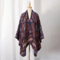 Detailed view of dark blue knitted poncho with orange paisley floral patterns on mannequin - Small Paisley / Slit Scarf / Navy Blue