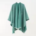 Detail of an elegant green knit poncho shawl with soft fringe edges and a textured finish. - 130*160cm / Green