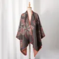 Detailansicht eines Damen-Strickponchos mit geometrischen Blumenmustern auf einer Schaufensterpuppe - Grau