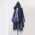 Side view of a hooded knit poncho with navy blue stripes and fringe detailing. - 135x150cm / Navy Blue