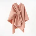 Close-up view of a peach knit poncho featuring a stylish diagonal strap and soft frayed edges - 130*160cm / Pink