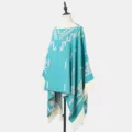 Eleganter türkisfarbener Strickponcho mit geometrischen Mustern und weißen Fransendetails - Hellblau