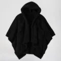 Close-up detail of the black fleece hooded cape showing cozy textured fabric and deep front pockets. - One Size / Black