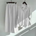 Detail view of women white cotton linen shirt and wide leg pants set hanging on wall. - S / Top And Bottom / White