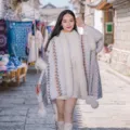 Damen Cape im Bohème-Stil aus Kunstkaninchenfell mit Zickzackmuster und dekorativen Pompons - Morgenmantel / Grauweiß