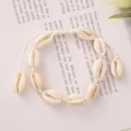 Detail shot of a handmade woven bracelet with natural cowrie shells on a soft background. - White Braided Rope with Tiger Shell (BR23Y0237-3)