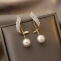 Macro view of gold wave earrings with sparkling crystals and a dangling pearl detail - Gold Wave Leaf With Artificial Pearl (ER22Y0110)