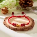 Detailed view of a handmade red woven bracelet with a golden snake charm for the Year 2025. - Simple Snake Cinnabar Beads Style (BR24Y0778-6)
