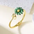Elegant gold-tone bangle featuring a green lacquered daisy and a delicate bee charm motif - Bangle / Green