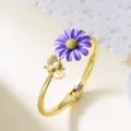 Elegant gold-toned bangle bracelet featuring a purple enamel daisy and a bee charm. - Bangle / Purple