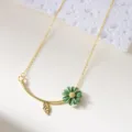 Elegant gold necklace featuring a green lacquer daisy pendant and delicate leaf charm - Necklace / Green