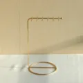 Close-up of a minimalist golden metal jewelry stand for necklaces and bracelets. - Gold