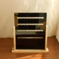 Detailed view of black acrylic earring display stand with wooden base and rows of slots. - Square 4 Rows / Natural Wood Base Black Board