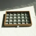 Detailed view of the 24-compartment walnut wood grain jewelry box with velvet lining. - 24 Grids Style / Walnut Color (Grey Interior)