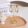 Detalle de soporte para joyas de metal dorado de 11,5 cm con base de bandeja de madera. - Organizador de Joyas en T de Metal