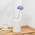 Close-up detail of artificial purple anthurium flower in minimalist white ceramic vase. - Purple Blue