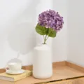 Artificial purple hydrangea flower detail in white ceramic vase desktop decor closeup aesthetic - Deep purple