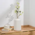 Gros plan d'un arrangement floral de lilas artificiel dans un vase en céramique blanche. - Vert