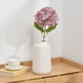 Artificial hydrangea flower arrangement in white ceramic vase detail shot home decor styling. - Purple