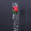 Einzelne künstliche rote Rose mit sternenmusterter transparenter Verpackungsfolie für Geschenke - Fuchsia