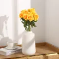 Künstlicher gelber Rosenstrauß mit weißer Keramikvase für die Tischdekoration zu Hause. - Orangegelb