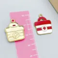 Red and white enamel medical kit charm pendant with cross symbol shown with ruler for scale - Red Medical Box Shape
