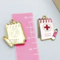 Medical notepad enamel charm in pink with red cross symbol and golden scale reference - 1 Piece (25*19mm)